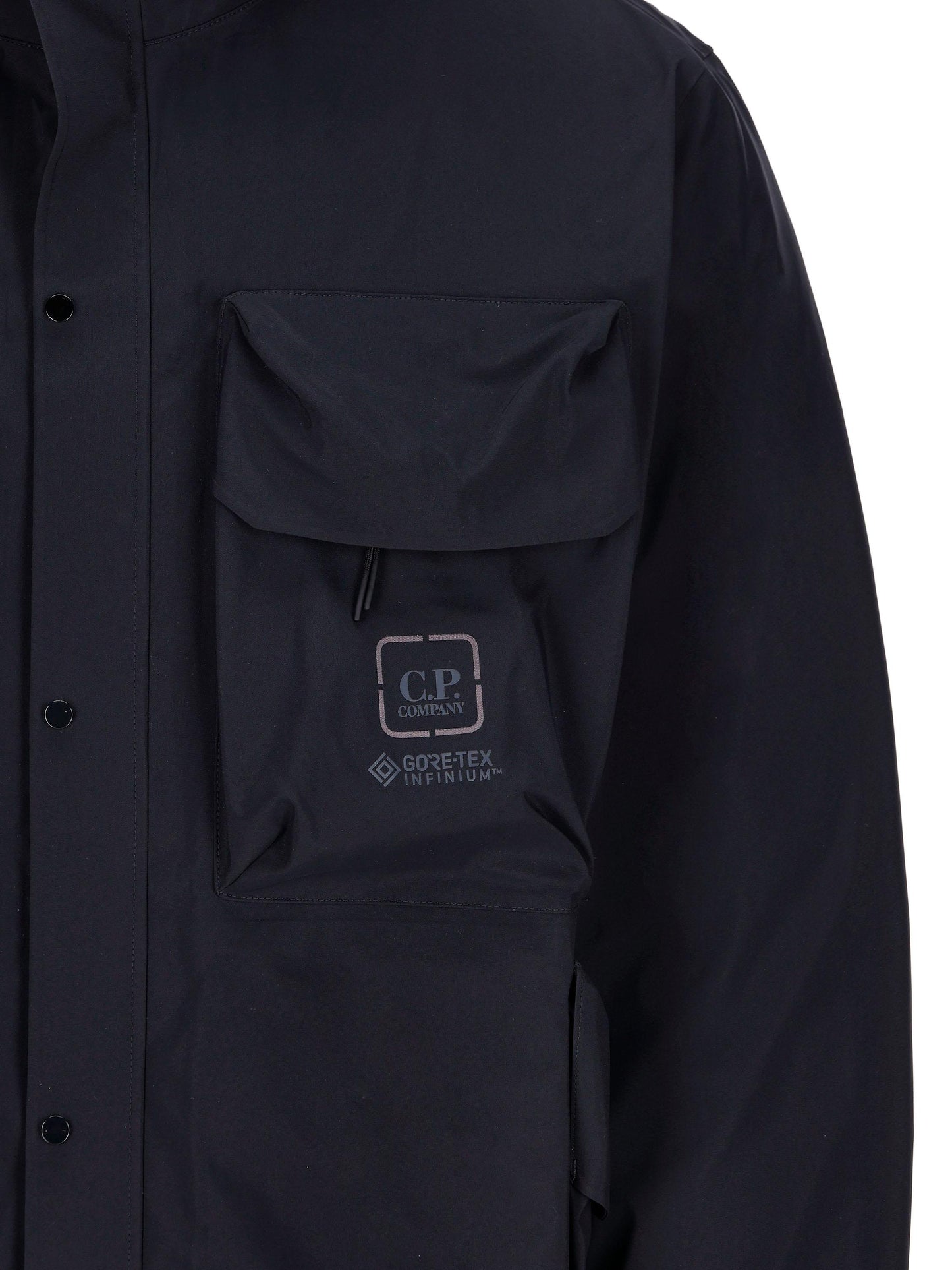 Giacca realizzata in poliammide di colore blu scuro, con maxi tasche sul petto con logo. 15CLOW007A 005967A888 C.P COMPANY 